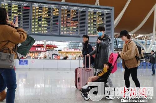 旅客帶著孩子前往辦票柜臺(tái)辦理登機(jī)手續(xù)。　殷立勤 攝
