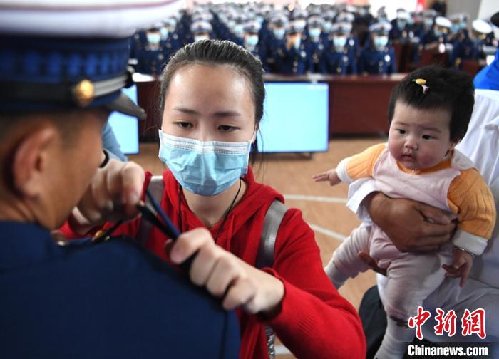 新消防員楊振的妻子彭莉與女兒現(xiàn)場(chǎng)見證丈夫加入“火焰藍(lán)”的神圣時(shí)刻。　劉忠俊 攝